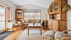 Un salon chaleureux avec un plancher en bois, un ensemble de canapés, une table basse, une bibliothèque et un meuble en bois.