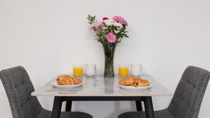 Una mesa de comedor con dos platos de croissants, dos vasos de zumo de naranja y dos tazas blancas.