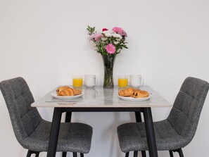 Una mesa de comedor con dos platos de croissants, dos vasos de zumo de naranja y dos tazas blancas.