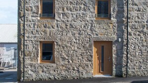 Un edificio de piedra con dos ventanas y una puerta de madera.