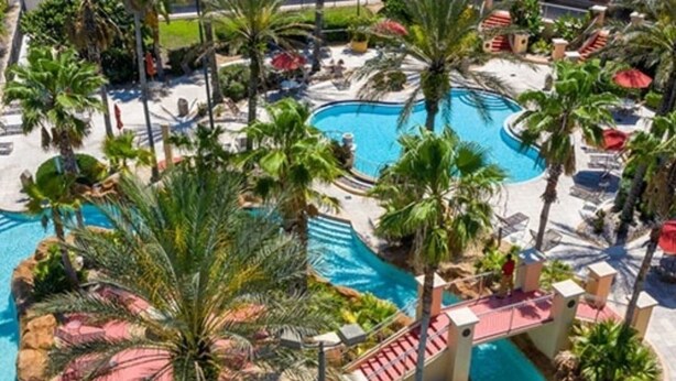 Un resort con varias piscinas, palmeras y zonas de descanso.