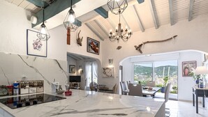 A spacious kitchen with a marble island, modern pendant lights, and a large window offering a view of the outdoors. - Vacation home Paulka by Interhome (Sainte Lucie Porto Vecchio)