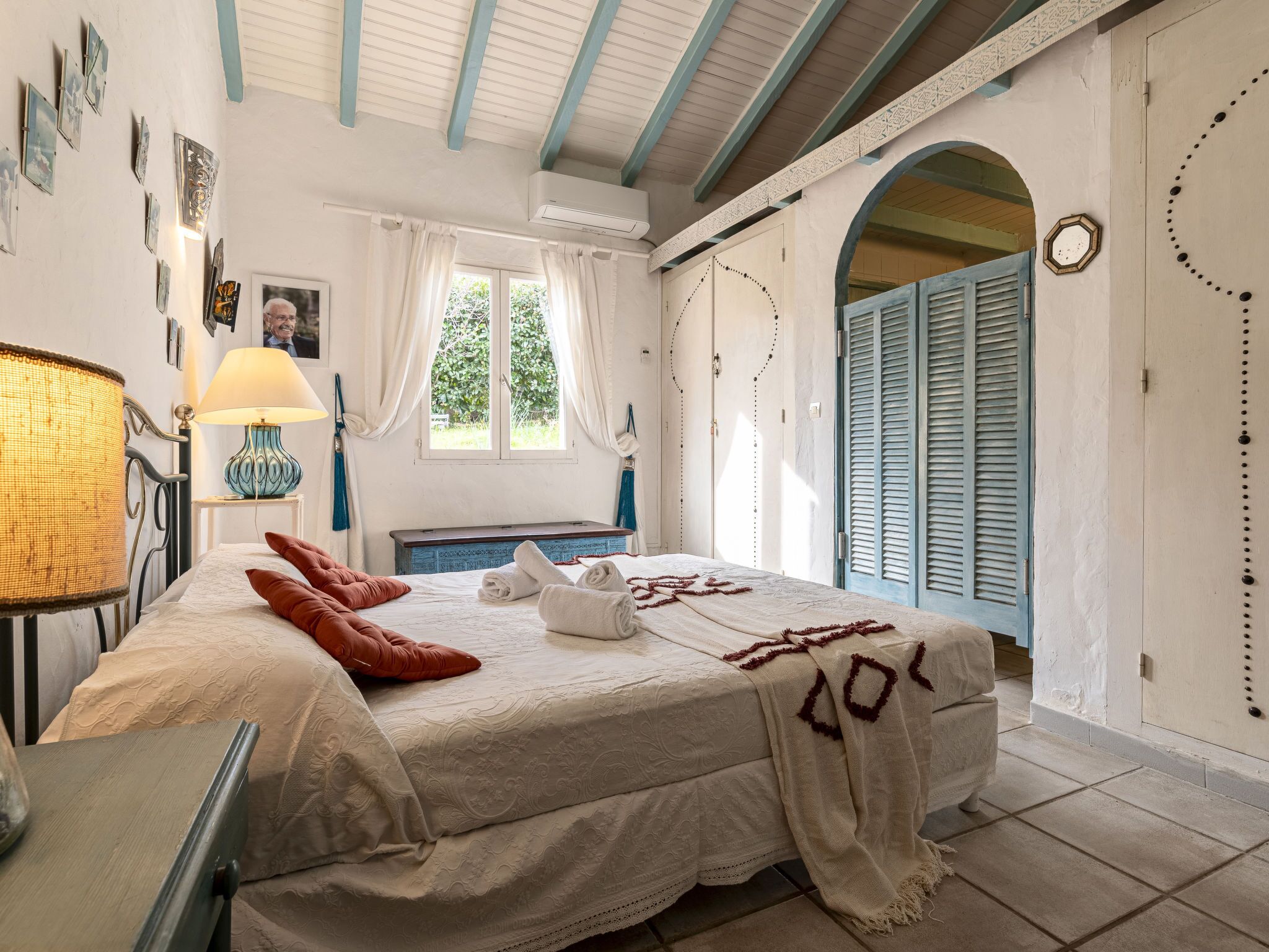 A bedroom with a bed, a lamp, a window, and a door.