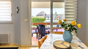 Ein Zimmer mit Esstisch, Stühlen, einer Vase mit Blumen und Blick durch eine Schiebetür auf eine Außenpatio-Terrasse.