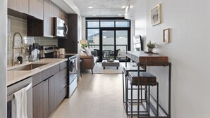 Een moderne keuken met donkerhouten kastjes, een roestvrijstalen spoelbak en een inbouwoven. Een groot raam biedt uitzicht op de omgeving.