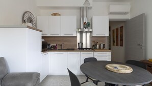 Een moderne keuken met witte kasten, een houten aanrecht en een eethoek met een ronde tafel en stoelen.