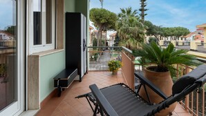 Een balkon met een zwarte stoel, een bankje en een bloempot.