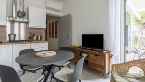 Een moderne keuken met een eethoek, een televisie en een rieten stoel.