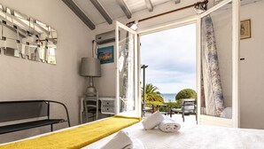 Une chambre d’hôtel avec un lit, un bureau, une chaise et une vue sur la mer.