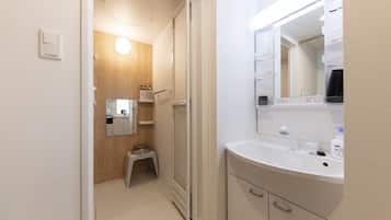 A bathroom with a shower, a sink, a mirror, and a toilet.
