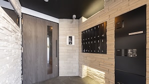 Un vestíbulo moderno con pared de piedra, un panel de control digital y una fila de taquillas.
