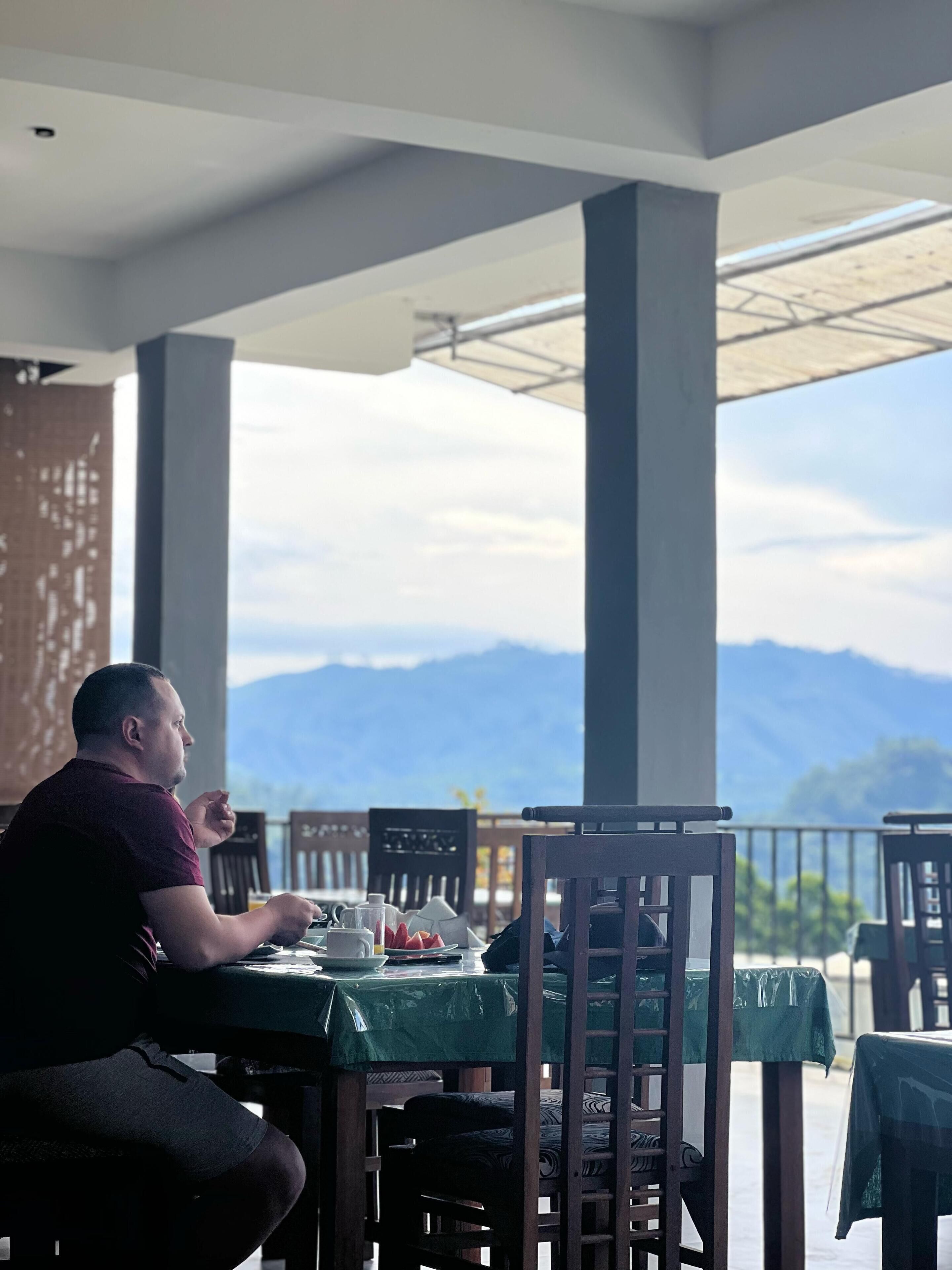 A man dining at a table with a mountain view.