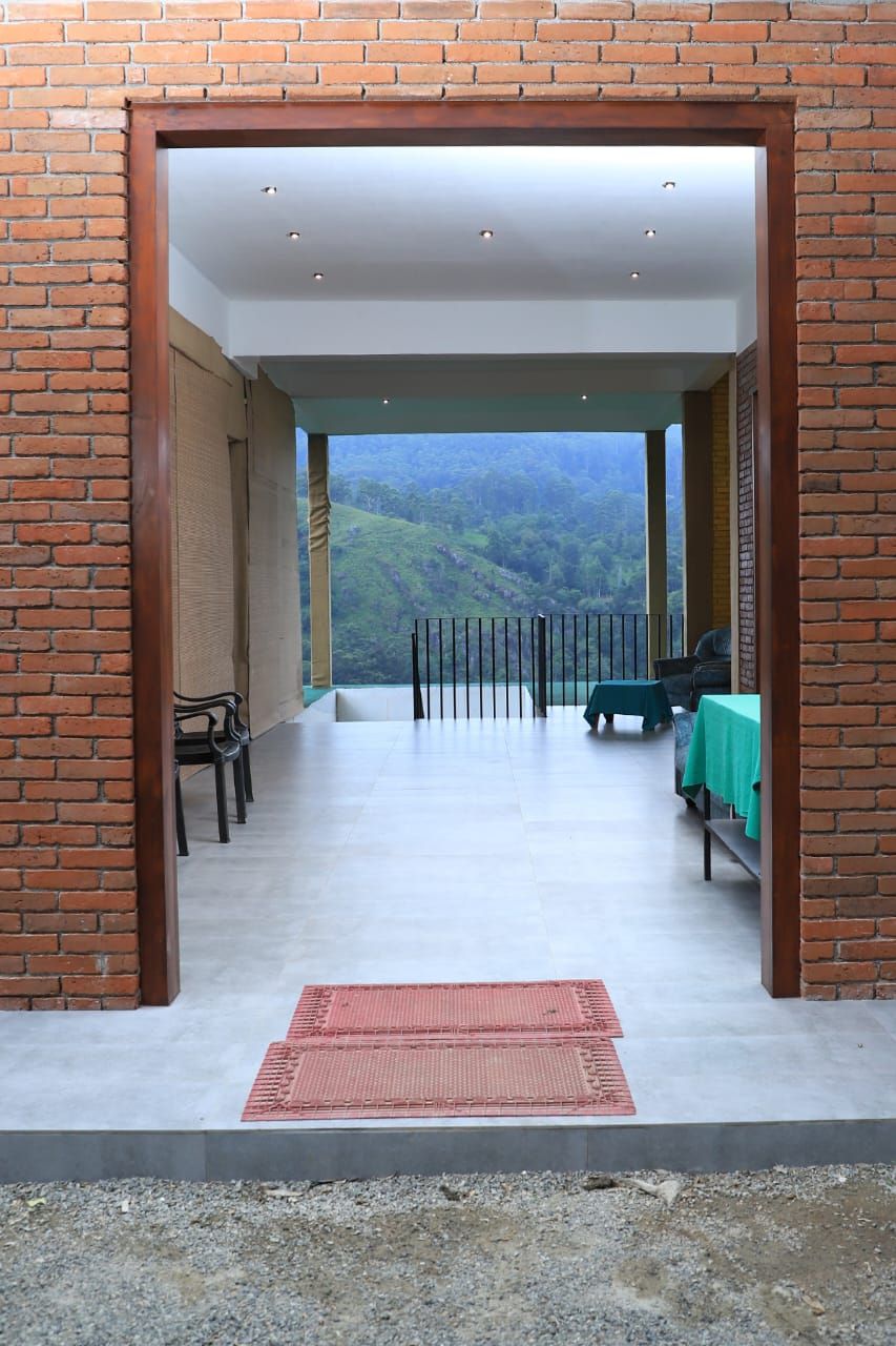 A covered outdoor area with a view of a mountainous landscape. There are chairs and a table with a green tablecloth.
