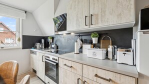 Eine moderne Küche mit weißen Schränken, einem eingebauten Backofen, einer Kaffeemaschine und einem Toaster.