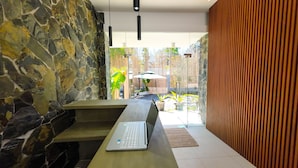 Un interior moderno con una pared de piedra, un banco de madera y un ordenador portátil sobre una mesa.