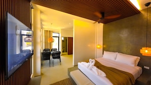 Habitación de hotel con cama, zona de comedor con sillas y vista al exterior.