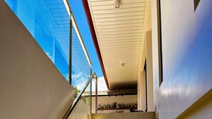 Una escalera con cerramiento de vidrio por un lado, que conduce a una zona de bar con botellas.