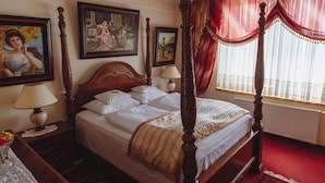 A four-poster bed with white linens, a wooden headboard, and a red and gold draped window treatment. - Hotel Grande (Celje)