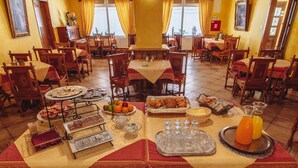A dining area with multiple tables set for breakfast, featuring pastries, fruits, and beverages. - Hotel Grande (Celje)