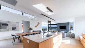 Une cuisine moderne avec un îlot central, un coin repas avec des chaises, un canapé et un téléviseur dans l’espace salon.