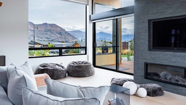 Un salon moderne doté d’une grande fenêtre, d’une cheminée et offrant une vue sur les montagnes.