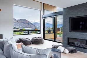 Ein modernes Wohnzimmer mit großem Fenster, Kamin und Bergblick.
