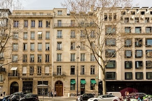 Un edificio de varios pisos con un estilo arquitectónico clásico, que presenta una entrada central con una gran puerta de madera y múltiples ventanas.