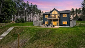 A two-story house with a stone foundation, a large front porch, and a landscaped yard.