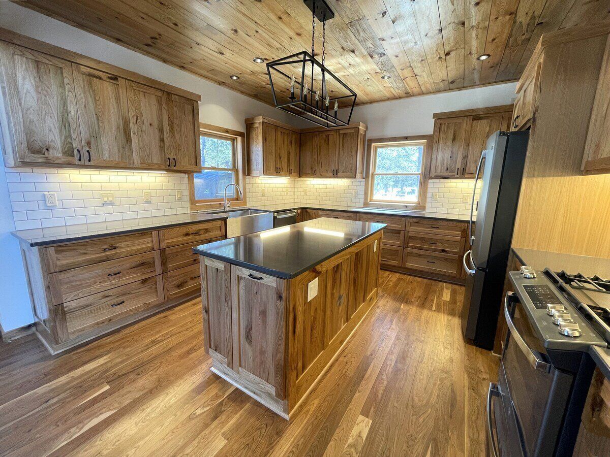 Une cuisine avec des meubles en bois, un îlot central, un réfrigérateur et une cuisinière.