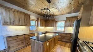 A kitchen with wooden cabinets, a central island, a refrigerator, and a stove.