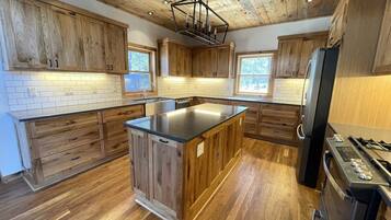 Une cuisine avec des meubles en bois, un îlot central, un réfrigérateur et une cuisinière.