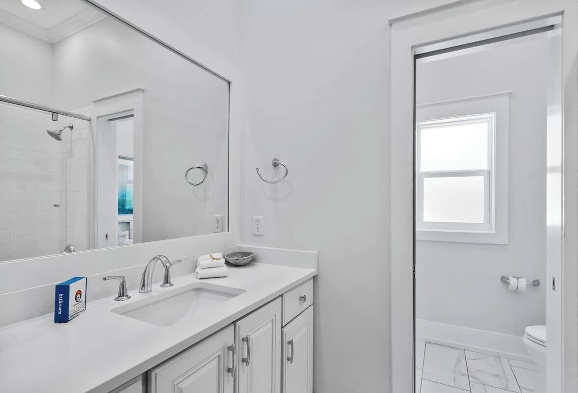 A modern bathroom with a white vanity, a large mirror, and a shower area.