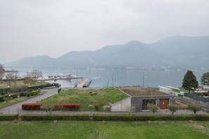 A lakeside view with a grassy area, a small building, and boats in the water. - Interno 18 in Clusane (Iseo)