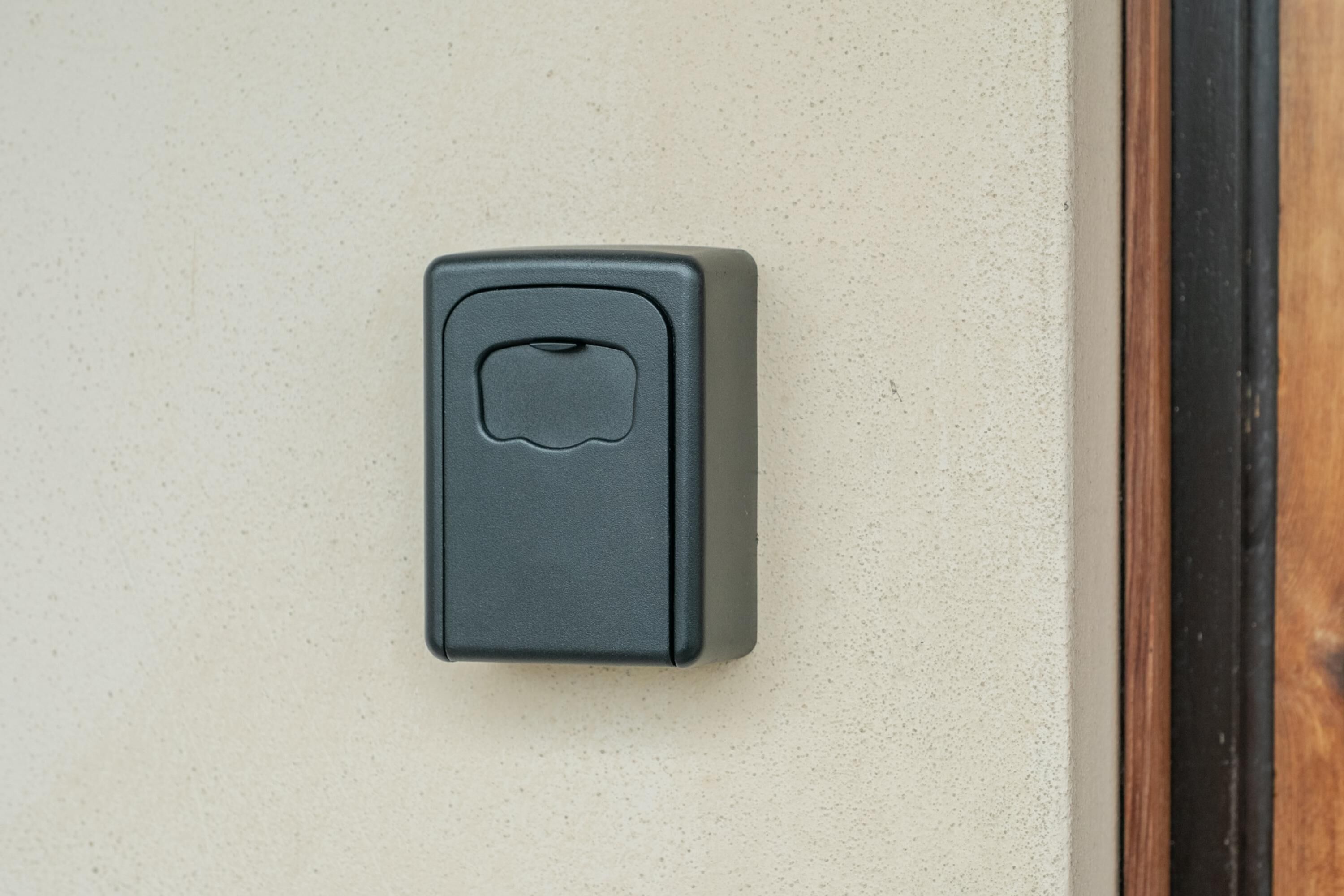 Un interphone gris fixé sur un mur de couleur beige.
