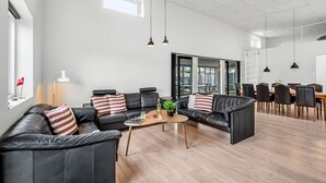 A spacious living area with leather sofas, a coffee table, and pendant lighting.