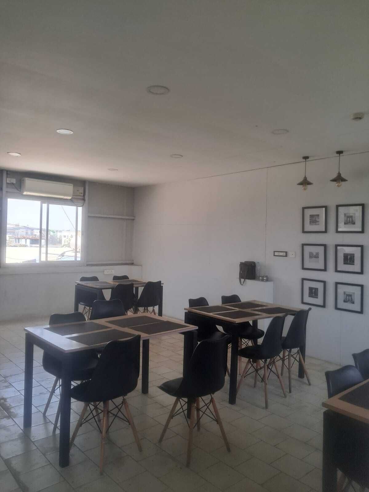Une salle de classe avec des tables et des chaises, une fenêtre donnant sur un paysage agréable et des tableaux encadrés accrochés au mur.