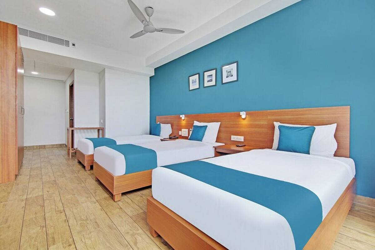 A hotel room with two beds, a ceiling fan, and a blue wall with framed pictures.