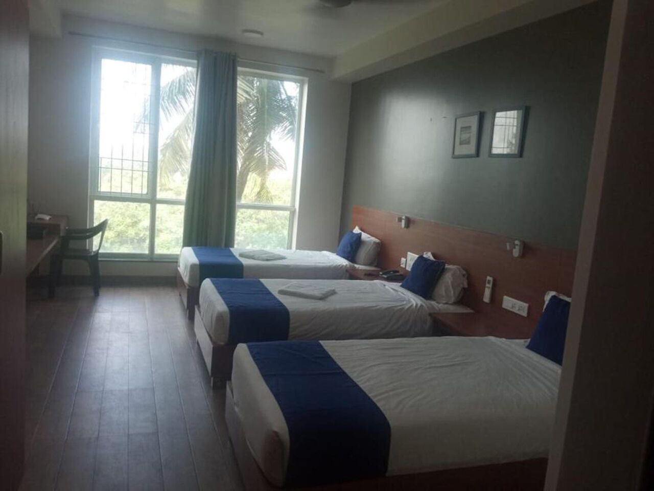 Habitación de hotel con dos camas, un escritorio y una ventana con cortinas.
