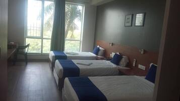 Habitación de hotel con dos camas, un escritorio y una ventana con cortinas.