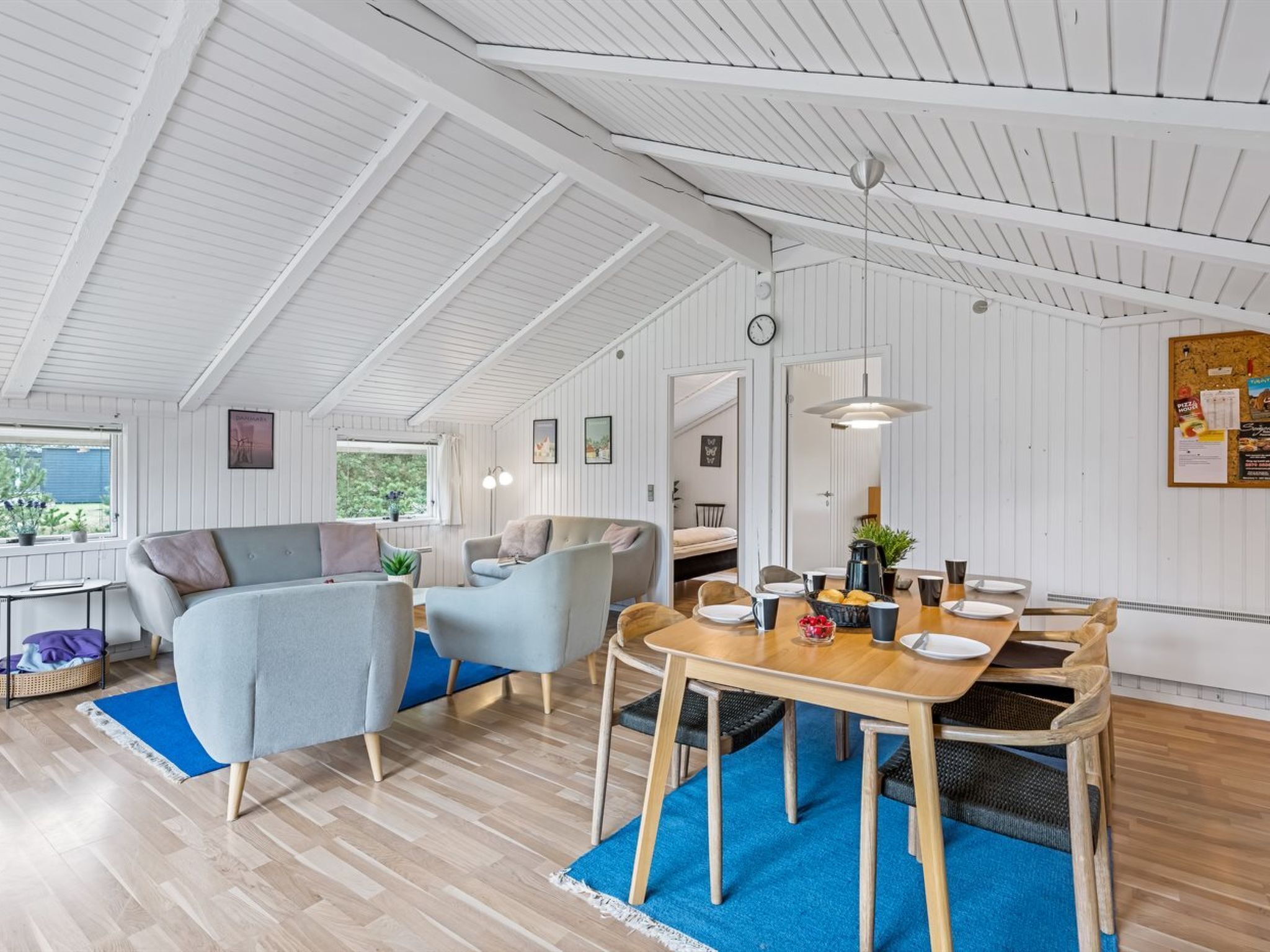 A spacious living area with a high ceiling, a dining table set for four, and a cozy seating arrangement.