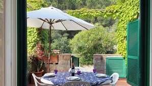 An outdoor patio with a table set for two, surrounded by greenery and a white umbrella. - Sant'Anna Volterraio - Maestra 56 - Sant'Anna del Volterraio - Maestra 56 (Rio dell'Elba)