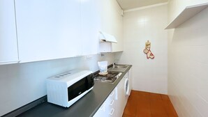 A compact kitchen with white cabinets, a microwave, a stove, and a washing machine. - Sant'Anna Volterraio - Maestra 56 - Sant'Anna del Volterraio - Maestra 56 (Rio dell'Elba)
