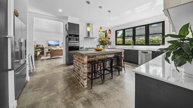 A modern kitchen with a central island, bar stools, and pendant lighting. - Bellmohr House on the Lake (Wentworth Falls)