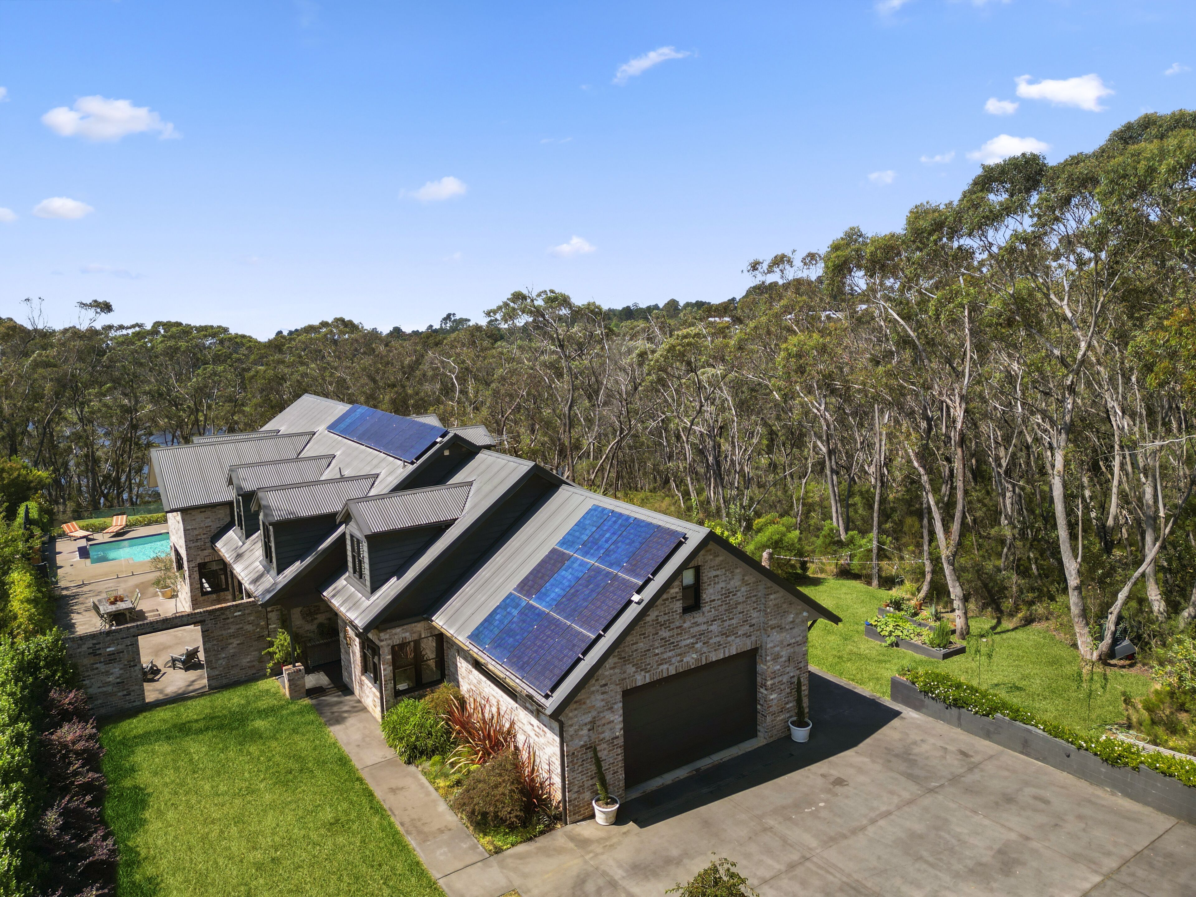 Une maison moderne dotée de panneaux solaires, d’une piscine et d’un jardin bien entretenu.