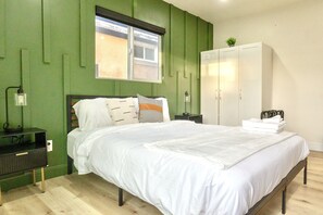 Ein Schlafzimmer mit Bett, Kleiderschrank, Nachttisch und Fenster.