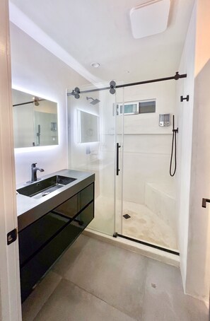Ein modernes Badezimmer mit einer begehbaren Glasdusche, einem Doppelwaschtisch und einem großen Spiegel.