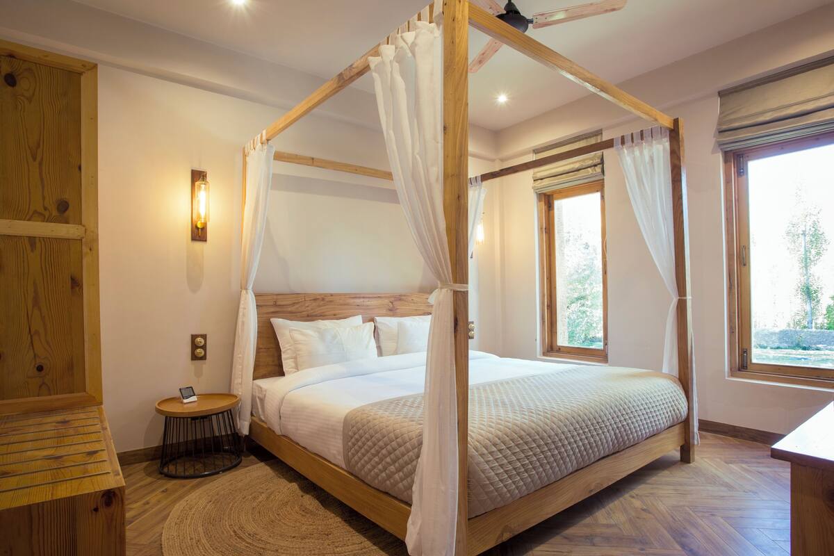 A four-poster bed with a canopy, a wooden headboard, and a bedside table with a lamp.