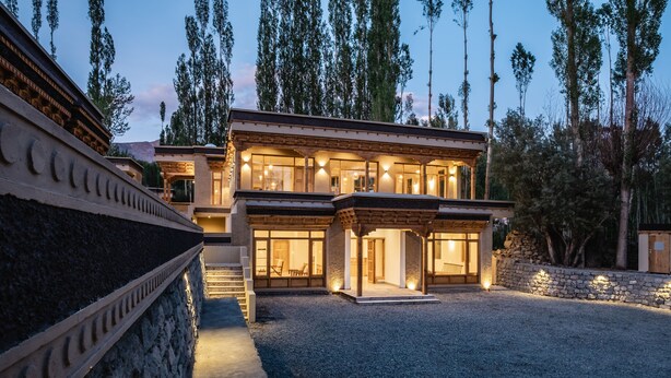Una casa moderna de dos pisos con fachada de piedra, ventanas amplias y camino de entrada de grava.