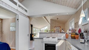 Une cuisine moderne avec des armoires blanches, une cuisinière encastrée et un grand îlot central doté d’un évier.