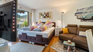 Une chambre à coucher avec un lit, une table de chevet, une commode et une fenêtre donnant sur un beau paysage.